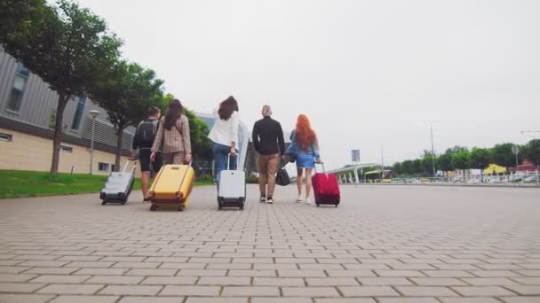 Mit Gepäck in der Hand machen sich fünf Reisefreunde auf den Weg zum Flughafenterminal. Touristen und Reisende gehen mit Gepäck auf Reisen. — Stockvideo