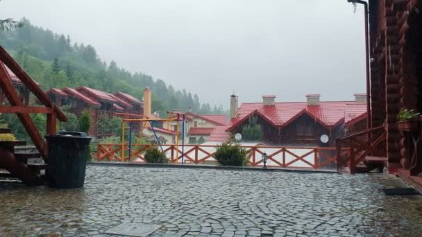 Lluvia fuerte cayendo en el patio de una casa de madera. Caen gotas de lluvia en el patio pavimentado de piedra y piedra . — Vídeos de Stock