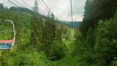 Güneşli bir yaz gününde, dağların panoramasında, teleferiğin sandalyesinden manzarayı izleyin. Güzel Karpat dağları ve teleferik dağın tepesine yükseliyor..