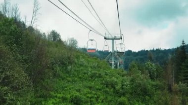 Güneşli bir yaz gününde, dağların panoramasında, teleferiğin sandalyesinden manzarayı izleyin. Güzel Karpat dağları ve teleferik dağın tepesine yükseliyor..