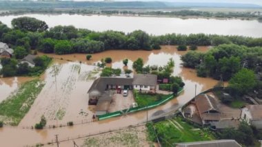 Yağmur yağdıktan sonra taşan bir nehrin kıyısındaki sel basmış bir evdeki insanlar. Ekolojik felaket, sel basmış köy ve evler