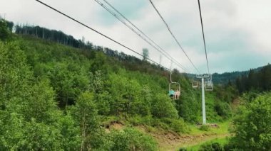Güneşli bir yaz gününde, dağların panoramasında, teleferiğin sandalyesinden manzarayı izleyin. Güzel Karpat dağları ve teleferik dağın tepesine yükseliyor..