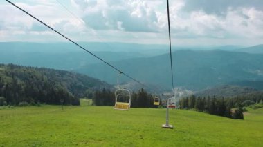 Güneşli bir yaz gününde, dağların panoramasında, teleferiğin sandalyesinden manzarayı izleyin. Güzel Karpat dağları ve teleferik dağın tepesine yükseliyor..