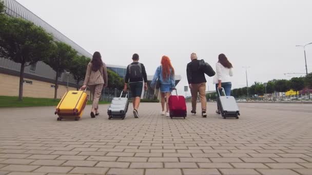 다섯 명의 여행하는 친구들은 짐을 들고 공항 터미널로 향한다. 관광객들 과 여행자들은 짐을 가지고 여행을 간다. — 비디오