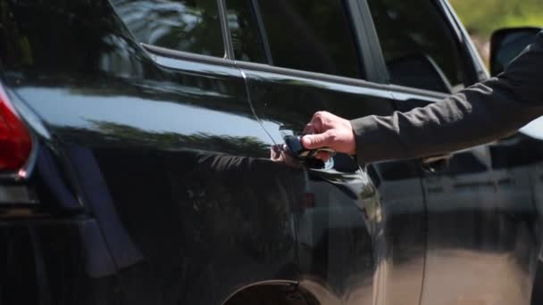 Mano masculina abre la puerta de un coche negro de clase ejecutiva. Silueta de una mujer en un vestido elegante se mete en un coche — Vídeo de stock