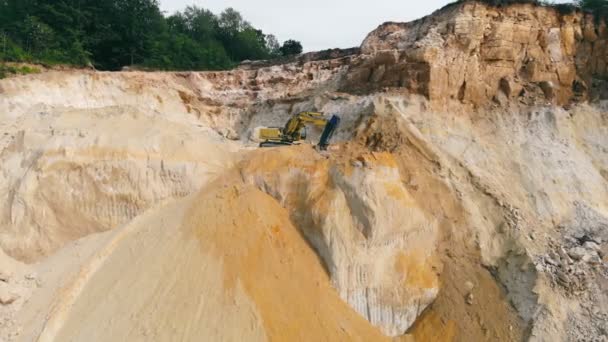 Escavatore che lavora in una cava di sabbia ed estrae sabbia. Un escavatore raccoglie la sabbia con un secchio e la scarica sul fondo della cava. — Video Stock