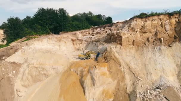 Bagger bei der Arbeit in einem Sandbruch und der Sandgewinnung. Ein Bagger hebt mit einer Schaufel Sand auf und kippt ihn auf den Grund des Steinbruchs. — Stockvideo