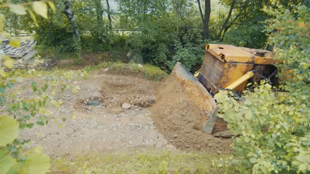 En bulldozer nivåer och reparerar en väg i bergen. Bulldozern rör sig långsamt och täcker stenarna på vägen. — Stockvideo