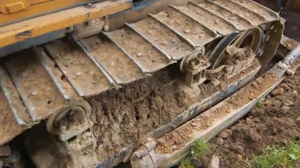 Närbild av larver och hjul på en bulldozer som kör på en grusväg. — Stockvideo