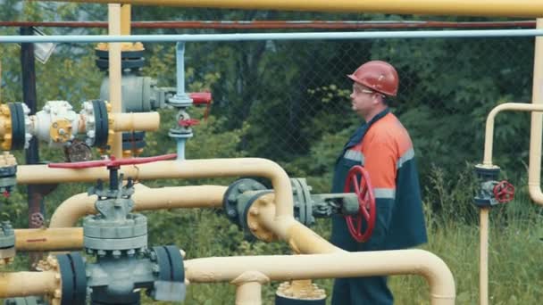 Ingeniero en el complejo de distribución de gas hace un desvío en la gasolinera. Un empleado de una compañía de producción de gas trabaja en una estación de producción de gas — Vídeos de Stock