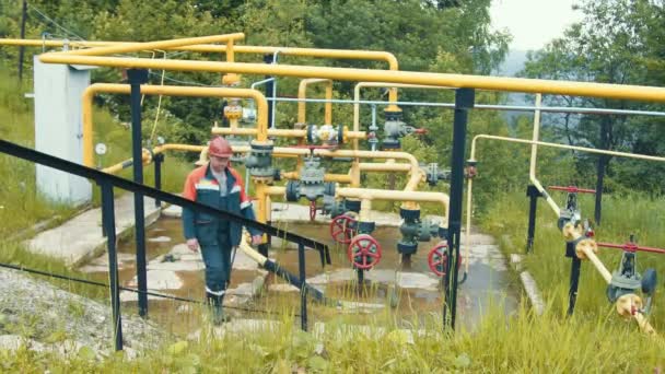 Ingeniero en el complejo de distribución de gas hace un desvío en la gasolinera. Un empleado de una compañía de producción de gas trabaja en una estación de producción de gas — Vídeo de stock