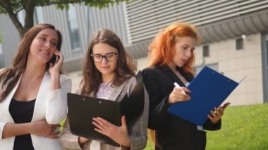 İş kadınları birbirleriyle iletişim kurar ve dosyaları dosyalarda görürler. Telefonda konuşan kız. İş kızları iş davalarını çözer ve gülümser.