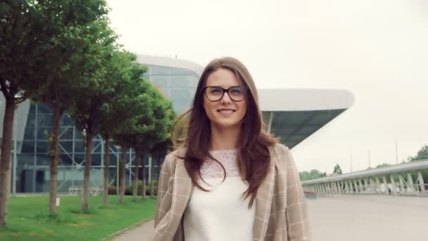 Πορτρέτο μιας όμορφης νεαρής κοπέλας που περπατάει και κοιτάζει την κάμερα στο φόντο του τερματικού του αεροδρομίου. — Αρχείο Βίντεο