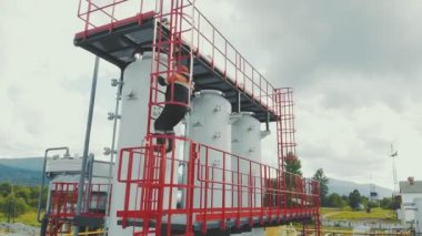 Hava manzaralı benzin istasyonu operatörü istasyonun tepesine tırmanır. Dağlardaki modern gaz kompleksi. Bir gaz işçisi gaz dağıtım ünitesinin merdivenini tırmanıyor.