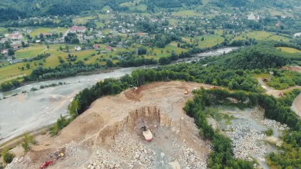 Vue aérienne Vol au-dessus d'une carrière dans les montagnes où des pierres et d'autres roches sont extraites. Machines lourdes travaillant dans une carrière sur le fond d'une rivière de montagne.