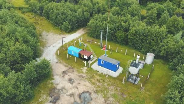 Vista aerea Un piccolo sito di produzione di gas situato in una zona montuosa circondata da una foresta verde. Stazione di produzione del gas. — Video Stock