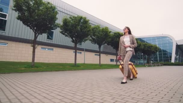 Γυναίκα που περπατάει με αποσκευές. Άφιξη ή αναχώρηση σε νέα χώρα. Μια επιχειρηματίας περπατά στο δρόμο με τις αποσκευές στο χέρι και εξερευνά την πόλη. — Αρχείο Βίντεο
