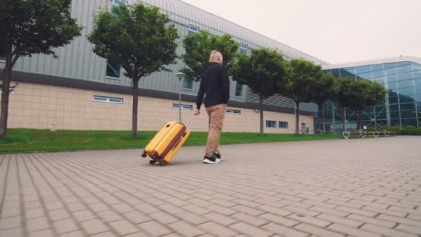 Homem de negócios faz uma viagem de negócios. Um homem vai para o aeroporto segurando bagagem em sua mão . — Vídeo de Stock