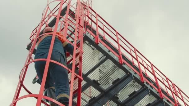 Bensinstationsoperatören klättrar upp till toppen av stationen. Modernt gaskomplex i bergen. En gasarbetare klättrar uppför gasfördelningsenhetens stege mot bakgrund av bergig terräng. — Stockvideo