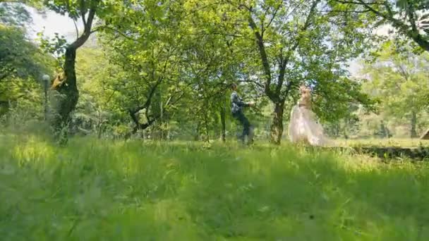 Jeune couple qui s'est rencontré dans les bois près des arbres sur un fond de soleil. Les jeunes mariés touchent doucement leurs mains et se regardent dans les yeux. — Video