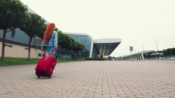 Mujer caminando con equipaje. La chica se va de viaje y camina hasta el aeropuerto. Una mujer de negocios camina por la calle con el equipaje en la mano y explora la ciudad . — Vídeos de Stock