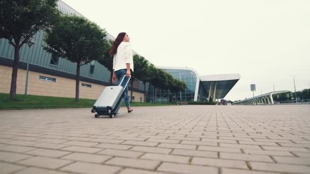 Kobieta z bagażem. Dziewczyna wyrusza w podróż i idzie na lotnisko. Bizneswoman idzie ulicą z bagażem w ręku i zwiedza miasto. — Wideo stockowe