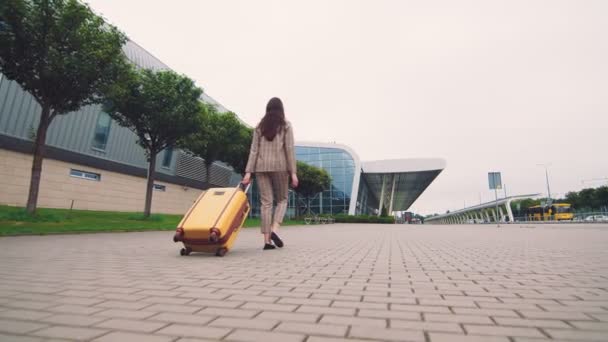 Frau zu Fuß mit Gepäck. Das Mädchen macht sich auf den Weg und läuft zum Flughafen. Eine Geschäftsfrau läuft mit Gepäck in der Hand die Straße entlang und erkundet die Stadt. — Stockvideo