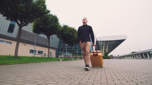 Férfi üzletember visszatér egy üzleti útról. Egy férfi bőröndöt tart a kezében.. — Stock videók