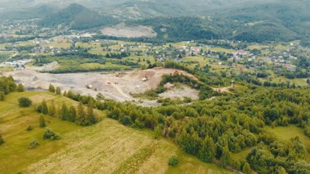 Flug über einen Steinbruch in den Bergen, wo Steine und andere Gesteine abgebaut werden. Schwere Maschinen arbeiten in einem Steinbruch am Hintergrund eines Gebirgsflusses. — Stockvideo