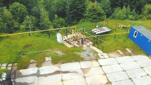 Luftaufnahme Eine kleine Gasförderstätte in einer bergigen Gegend, die von grünem Wald umgeben ist. Tankstelle. — Stockvideo