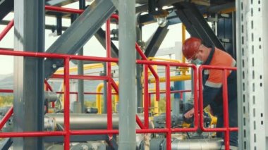 Benzin istasyonunun çalışanı koruyucu bir tıbbi maske takıyor, benzin dağıtım istasyonu gaz tedarik vanasını çeviriyor ya da söküyor. Benzin istasyonunda çalışan bir benzin üreticisi..