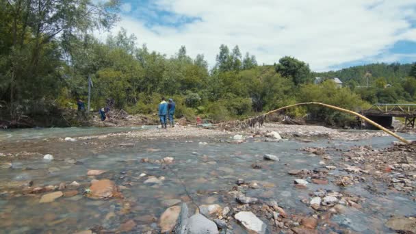Ukraine. Nadvirna 24 juin 2020. Le cours d'une rivière de montagne après les inondations. Restes d'arbres et de pierres après l'inondation dans la rivière de montagne. Femme traverse le pont sur la rivière. — Video
