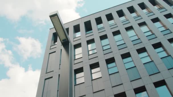 Onderdeel van de gevel van een modern business center gebouw is een bottom-up uitzicht. De lucht weerkaatst in de ramen van het gebouw. — Stockvideo