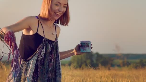 Il volto di una donna che sorride mentre dipinge un quadro con una manciata improvvisata di grano imbevuto di vernice. Pervani che disegnano un quadro in un campo al tramonto con vernice di grano. — Video Stock