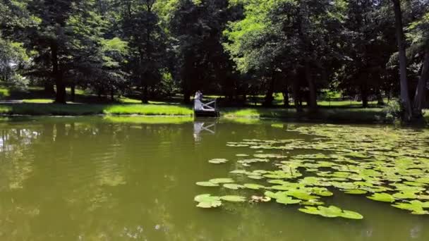 Pemandangan udara Pengantin baru pada hari pernikahan mereka berdiri di sebuah jembatan kayu di tepi danau — Stok Video