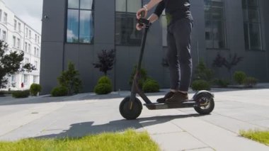 Elektrikli ekolojik scooter kullanan bir adamın bacakları. Bir adam elektrikli scooter platformunda durur ve....