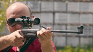Optik tüfek görüşüne bakarken nişan alan bir adamın yüzünü kapatın..