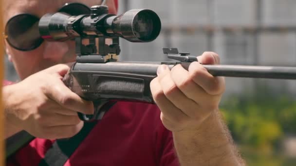 Κοντινό πλάνο του προσώπου ενός άνδρα που σημαδεύει ενώ κοιτάζει ένα οπτικό σκοπευτικό όπλο. — Αρχείο Βίντεο
