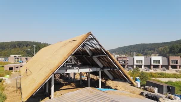 Acoperișul unei case mari cu paie uscată și fân. Lucrătorii care instalează acoperișul . — Videoclip de stoc
