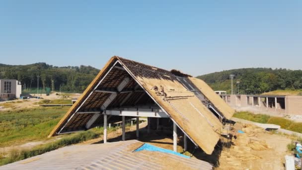 Aerial view the roof of a large house with dry straw and hay. Workers who install the roof. — Stock Footage Aerial view the roof of a large house with dry straw and hay. Workers who install the roof. Royalty Free Stock Footage
