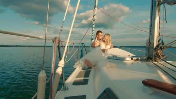 Brides sit on a yacht, looking at each other. Beautiful landscape behind them. The bride smiles tenderly at the groom — Stock Video