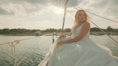 Gün batımında bir yatta gelin. Gelinler uzaktan bakar, güneş ışınları