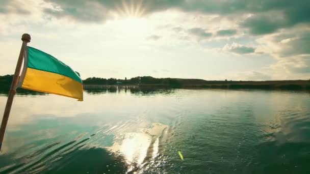 Moteur de croisière éclaboussure sur le lac d'eau douce. Vue arrière du bateau de plaisance en mouvement, y compris le moteur du bateau. Drapeau de l'Ukraine sur un fond de coucher de soleil — Video