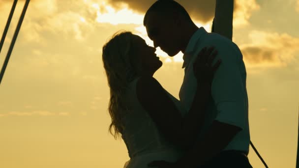 Silhouette nera di due amanti. Sposi novelli al tramonto. Lo sposo bacia la sposa e la abbraccia teneramente al tramonto — Video Stock