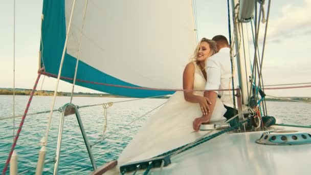 新婚旅行はヨットに乗って湖を航海しています。閉じられた花嫁は若い男の手を撫でて微笑んだ — ストック動画