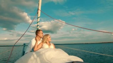 Gelin ve damat bir yatta oturuyorlar. Gün batımında uzaklığa bakıyorum. Bulutların ve göllerin güzel manzarası