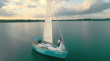 Ukrayna. Lviv. 19.09.2020. Gün batımında kuş bakışı deniz manzaralı bir yat. Gökyüzü suya yansıyor. Gün batımında yelkene tepeden bakan yatın yanında.
