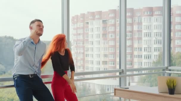 Des hommes d'affaires dansant dans le bureau. Une femme heureuse et un homme dansant ensemble près de la fenêtre. Danse de deux jeunes — Video