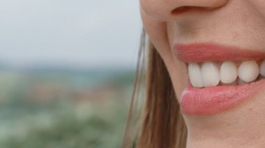 Mükemmel beyaz dişleri olan çekici bir kızın gülümsemesi kameraya yan çevrilmiş. Mükemmel beyaz dişler ve bir gülümseme. Yan görünüm.