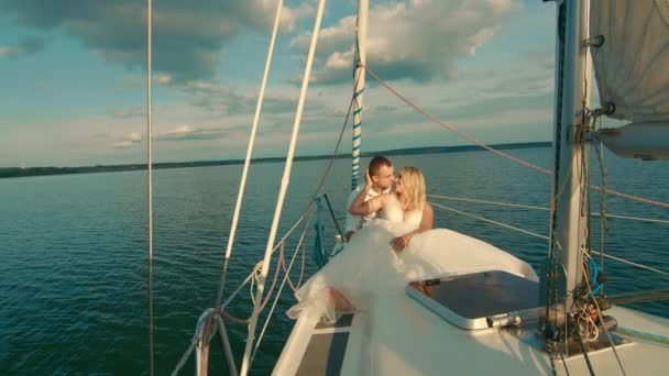 Les mariées s'assoient sur un yacht, se regardant. Beau paysage derrière eux. La mariée sourit tendrement au marié — Video